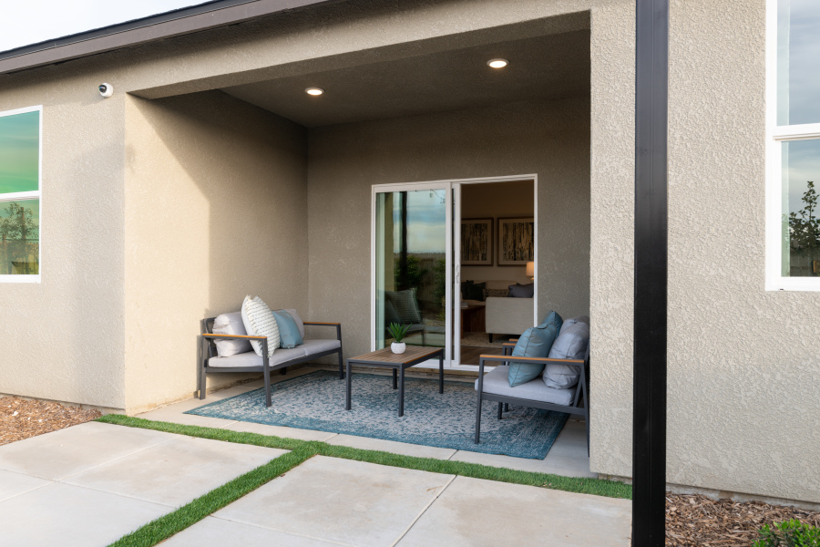 A room with a glass door and a patio with chairs and a table.