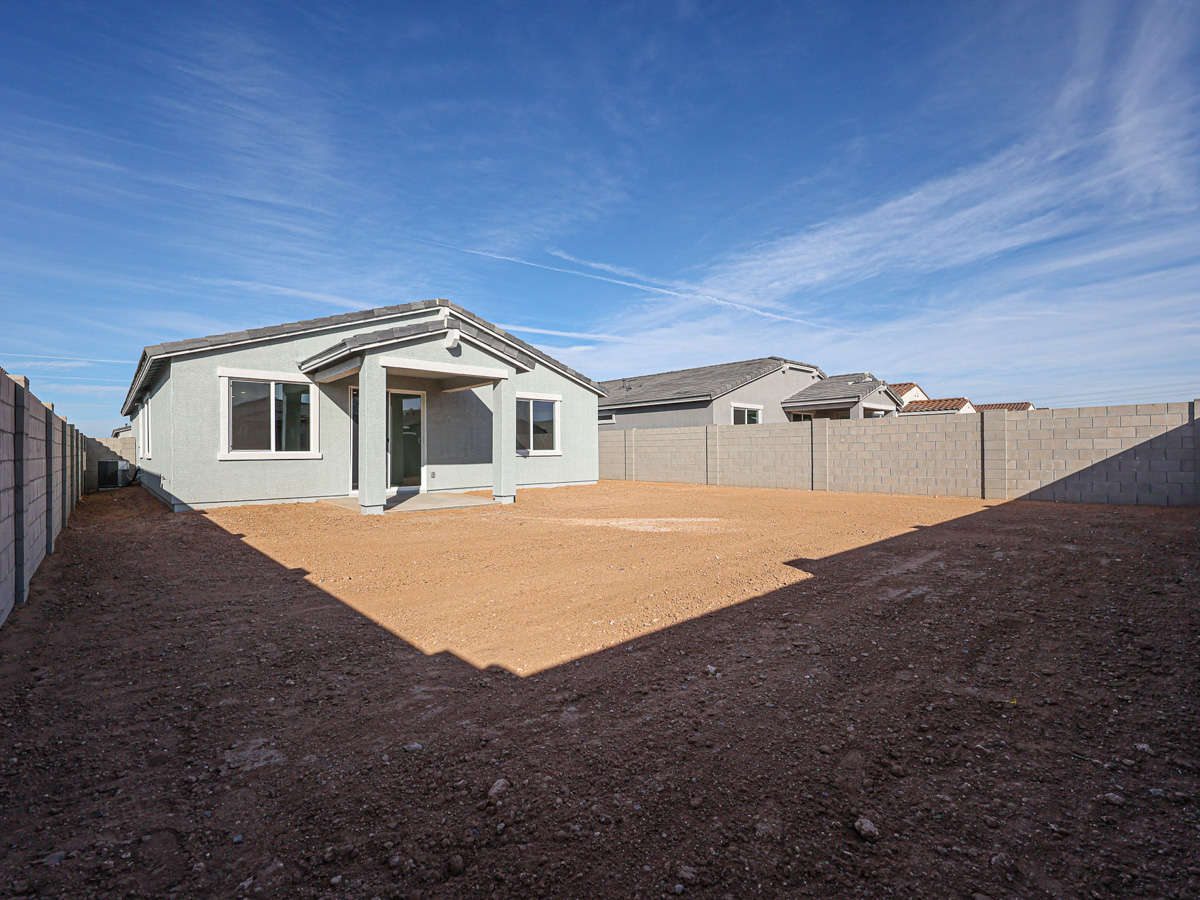 A dirt yard with a house in the background.