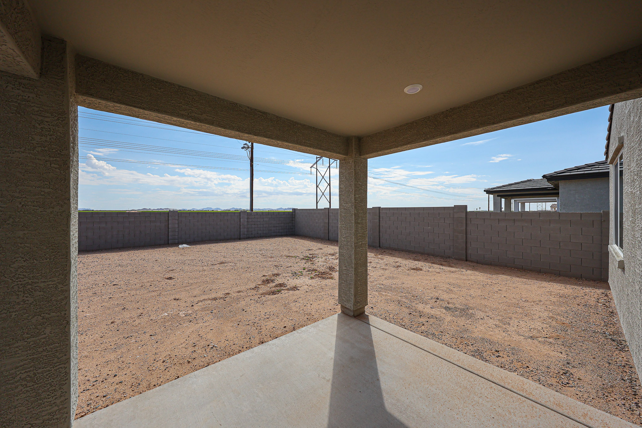 A concrete walkway with a fence and a building in the background.
