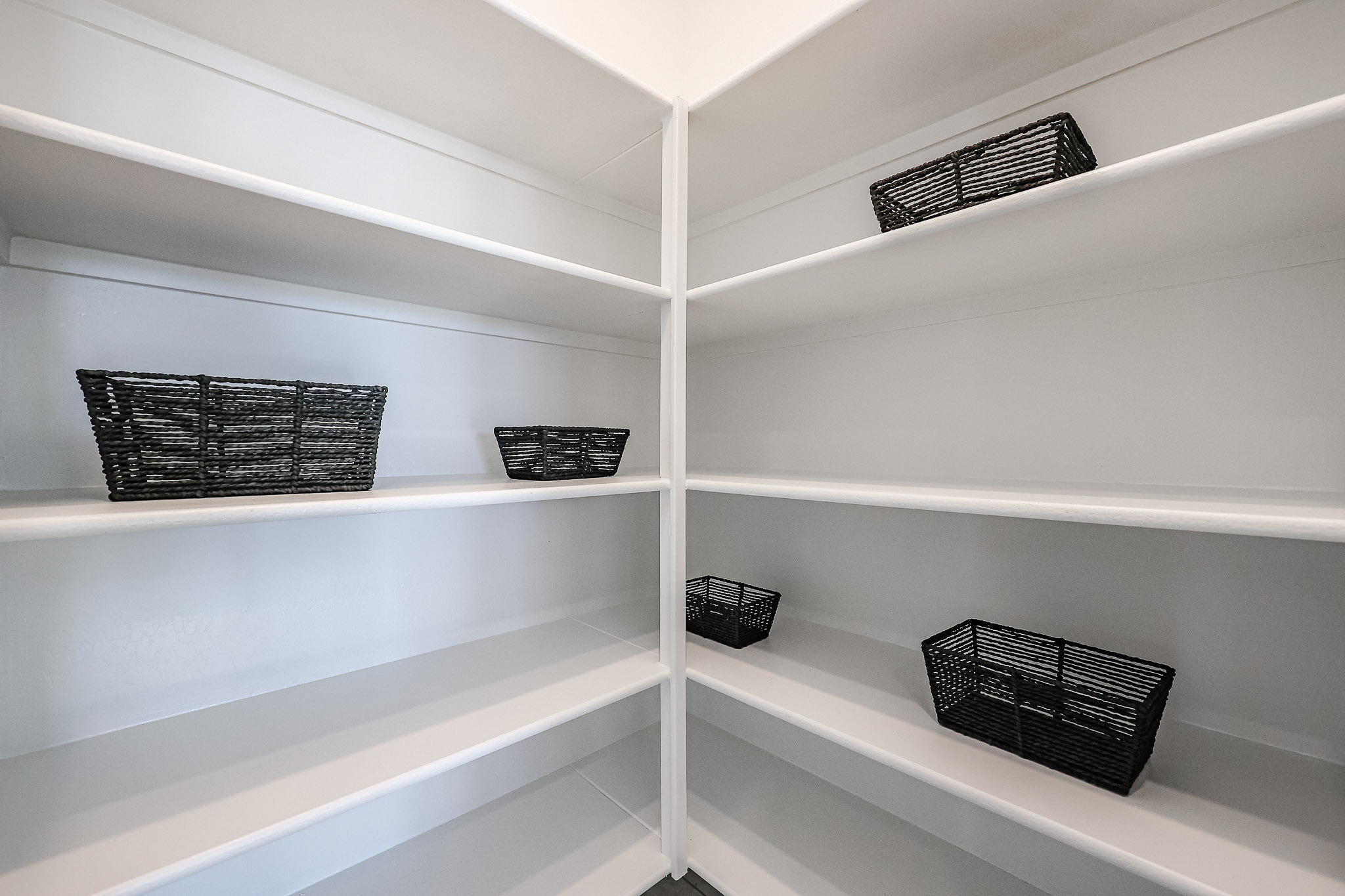 A white shelf with baskets and baskets.