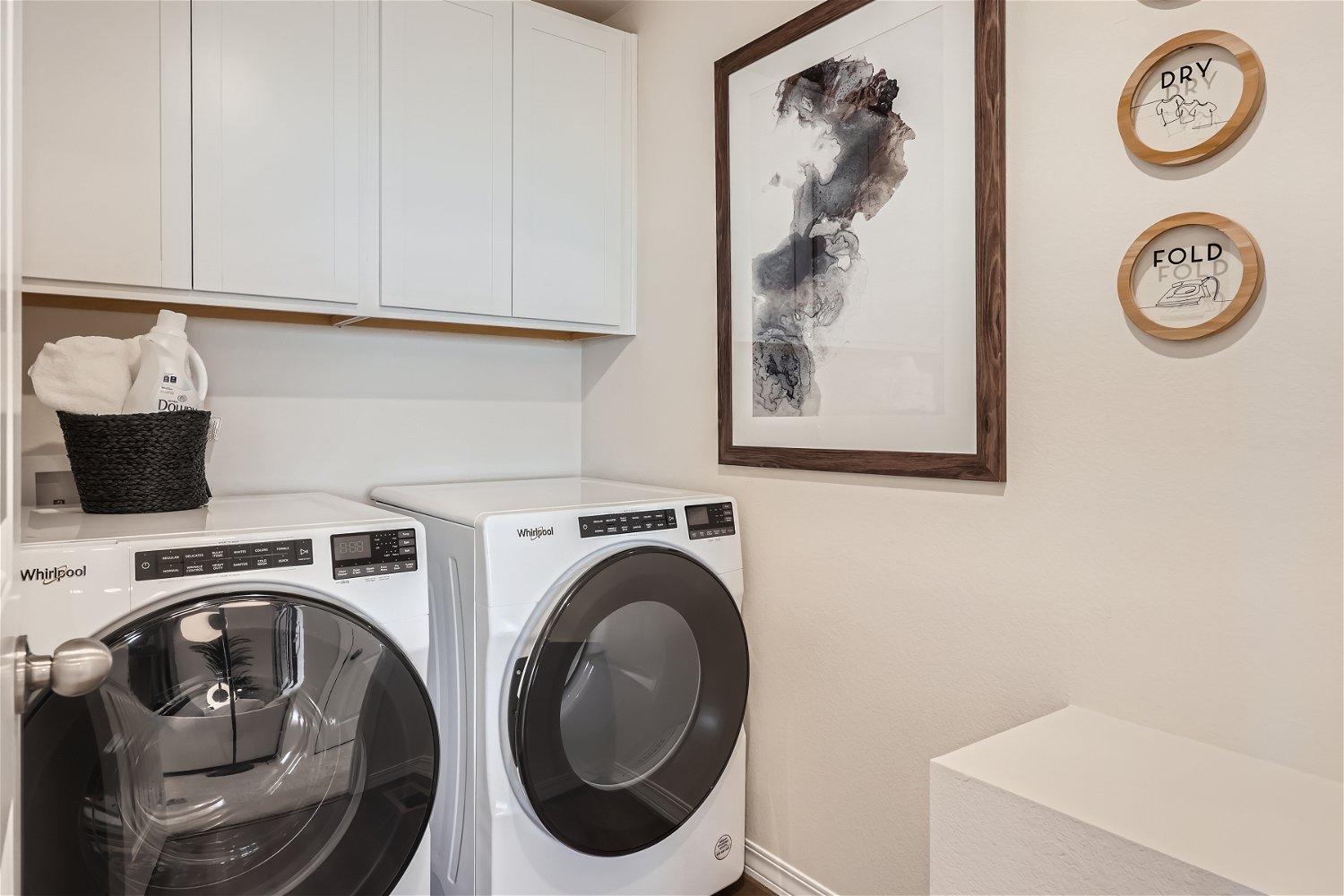 A laundry room with white cabinets.