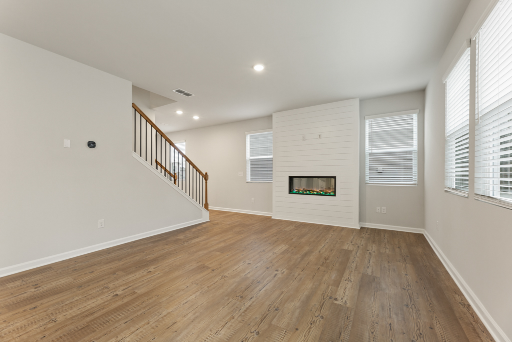 A room with a wood floor and a wood floor with a staircase.