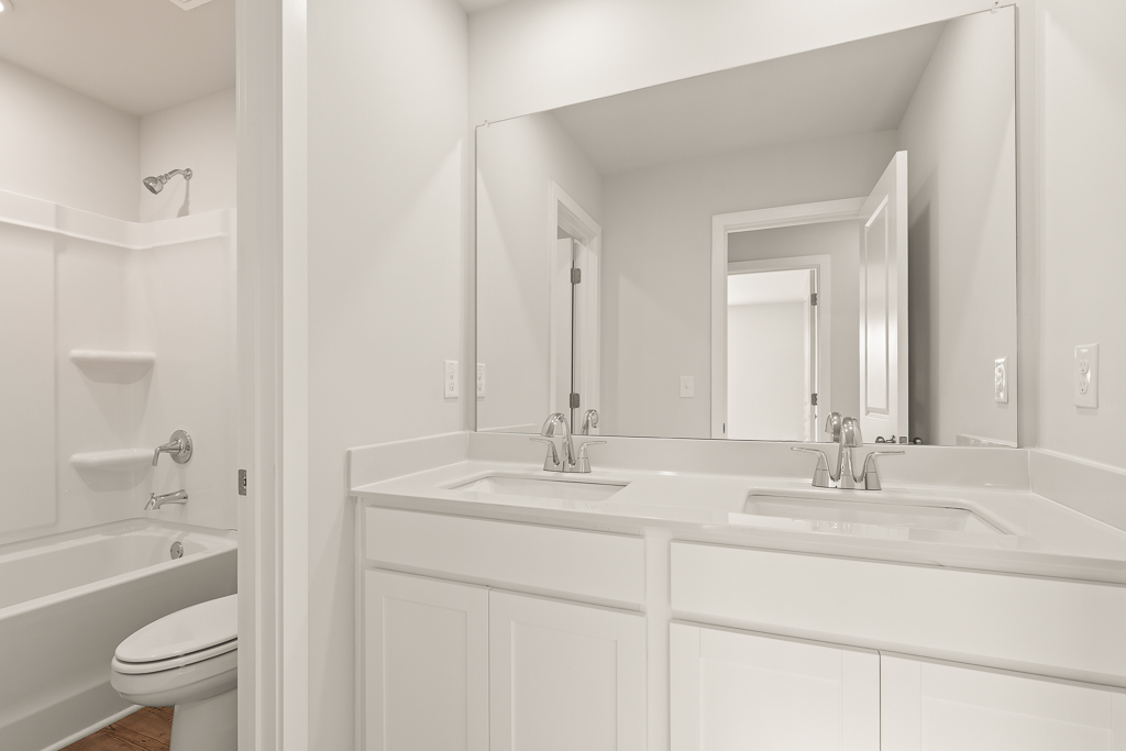 A bathroom with a sink toilet and mirror.