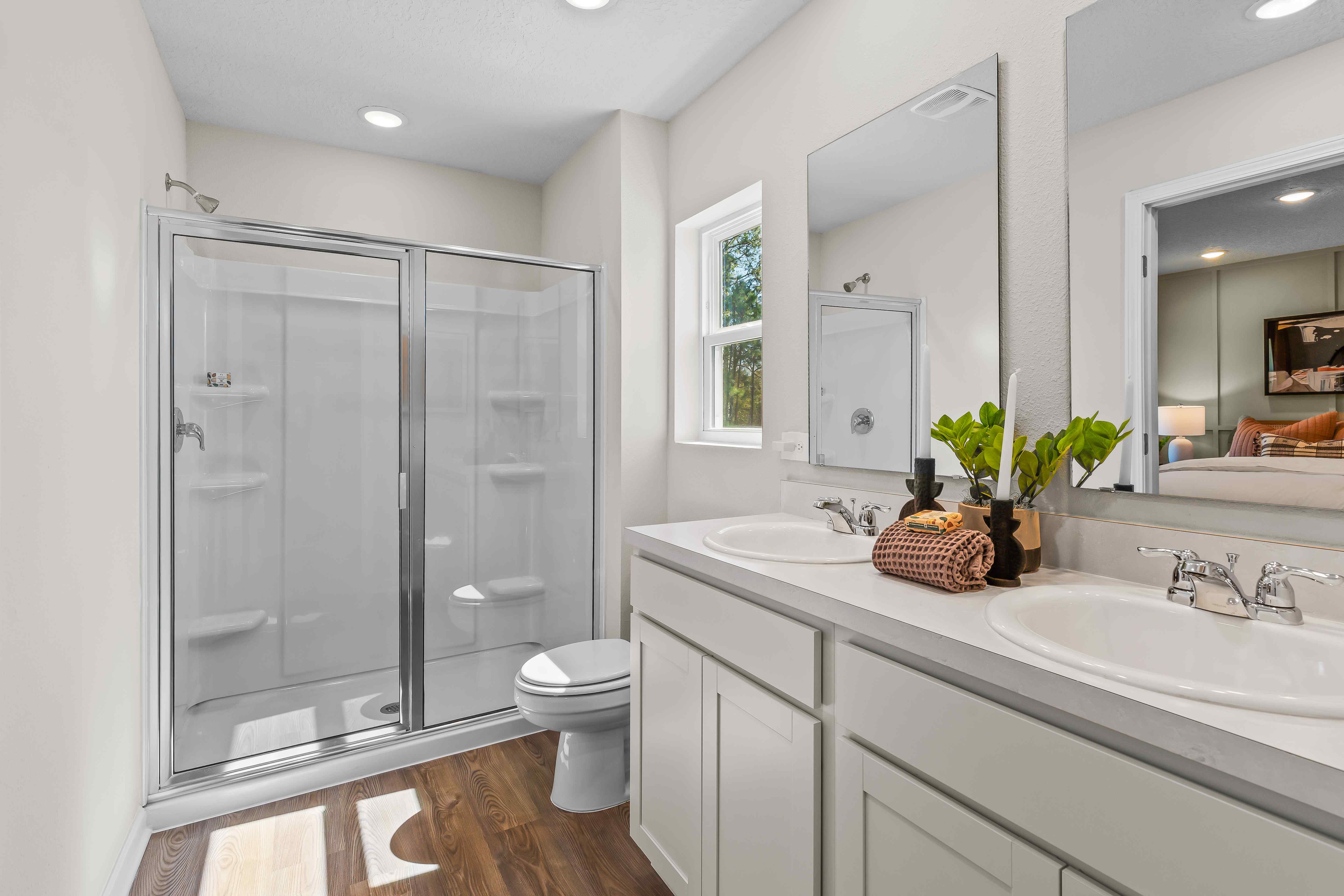 Davor Model Paired Home Primary Bathroom with White Cabinets and Shower at The Landings at Pecan Park