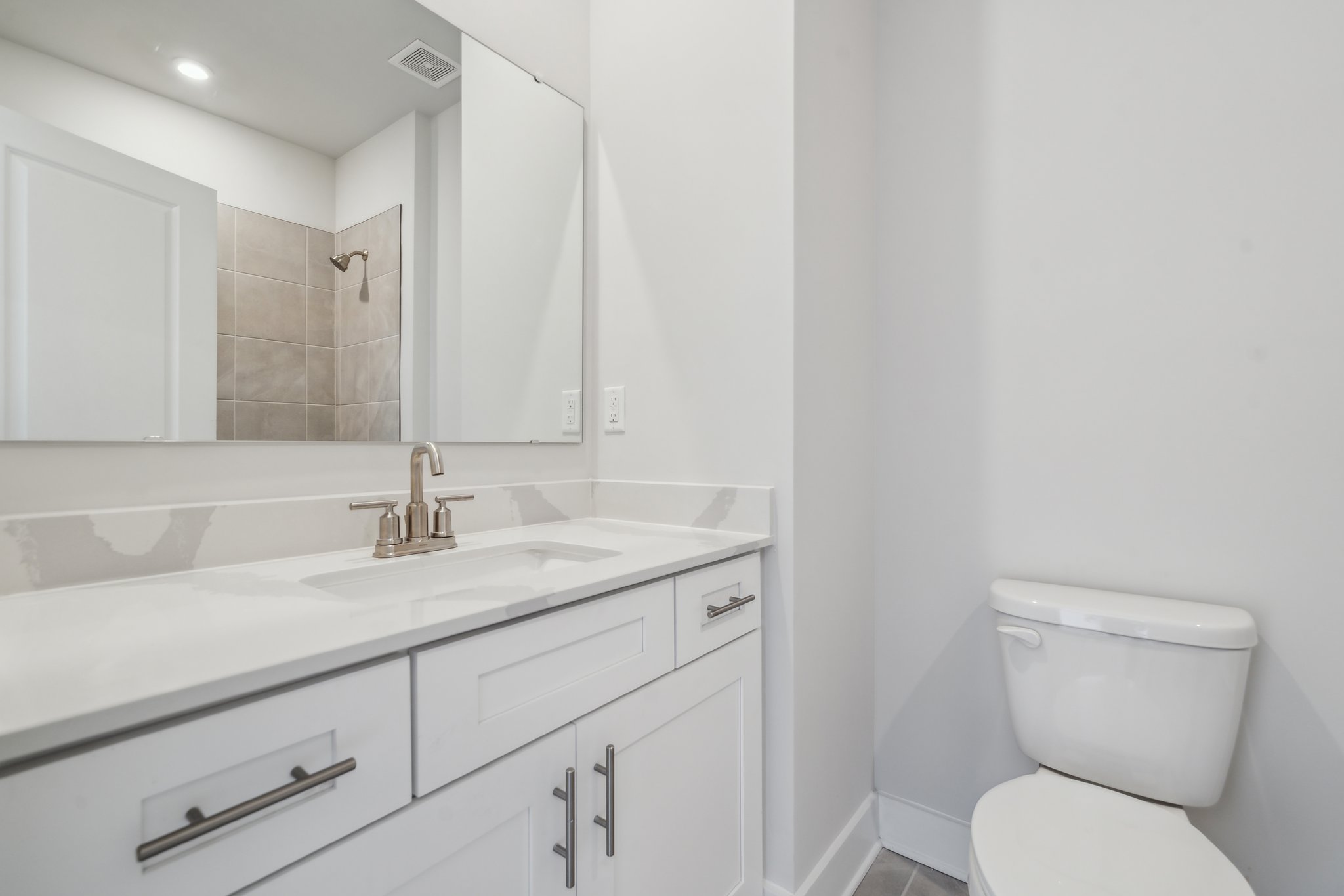 A bathroom with a sink toilet and mirror.