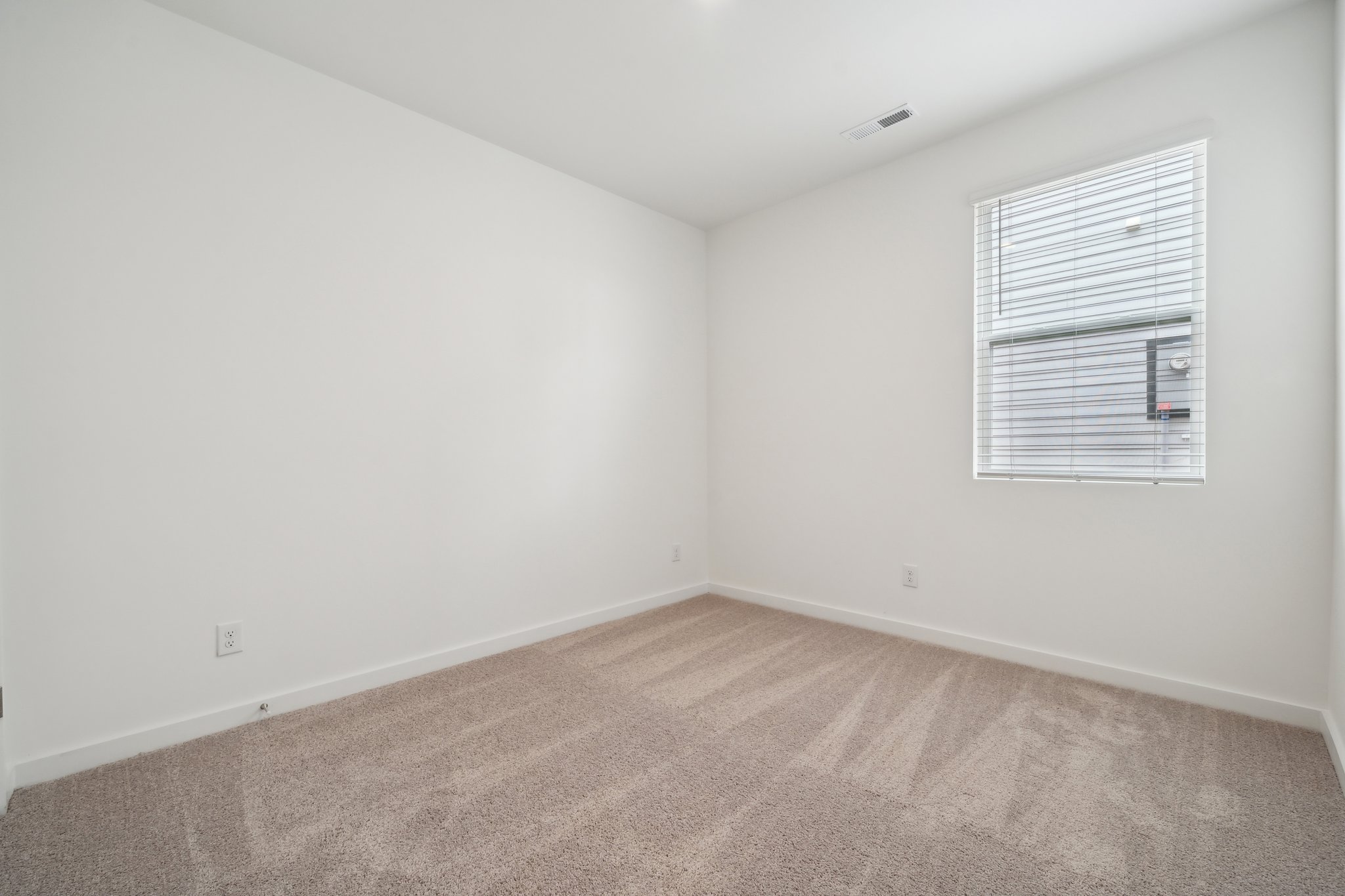 A room with a carpet and a window.