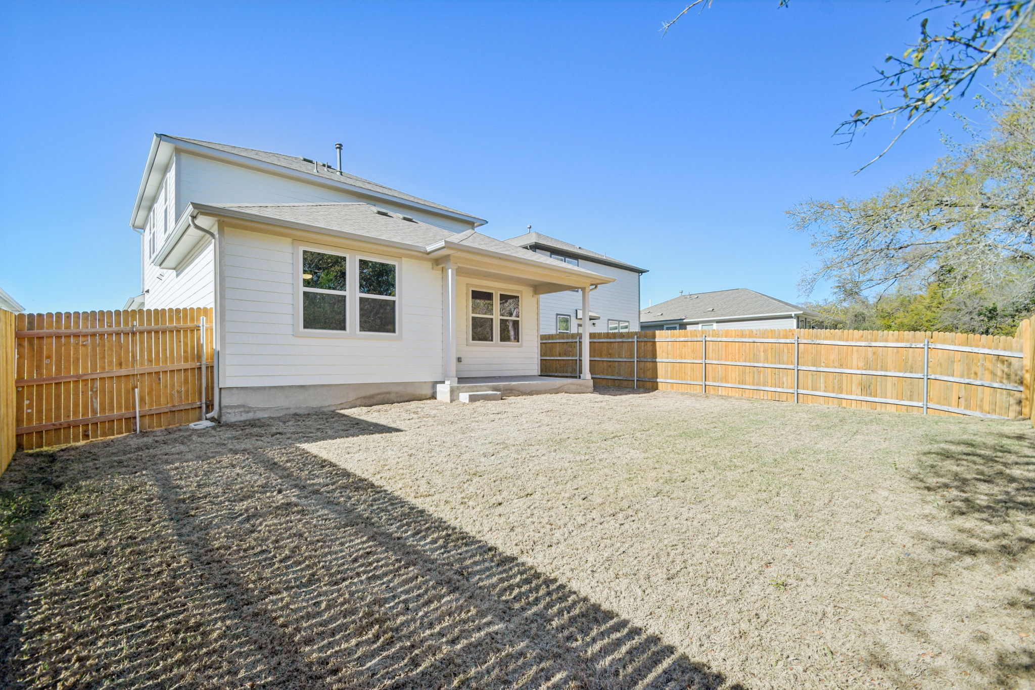 A house with a fence and dirt in front of it.