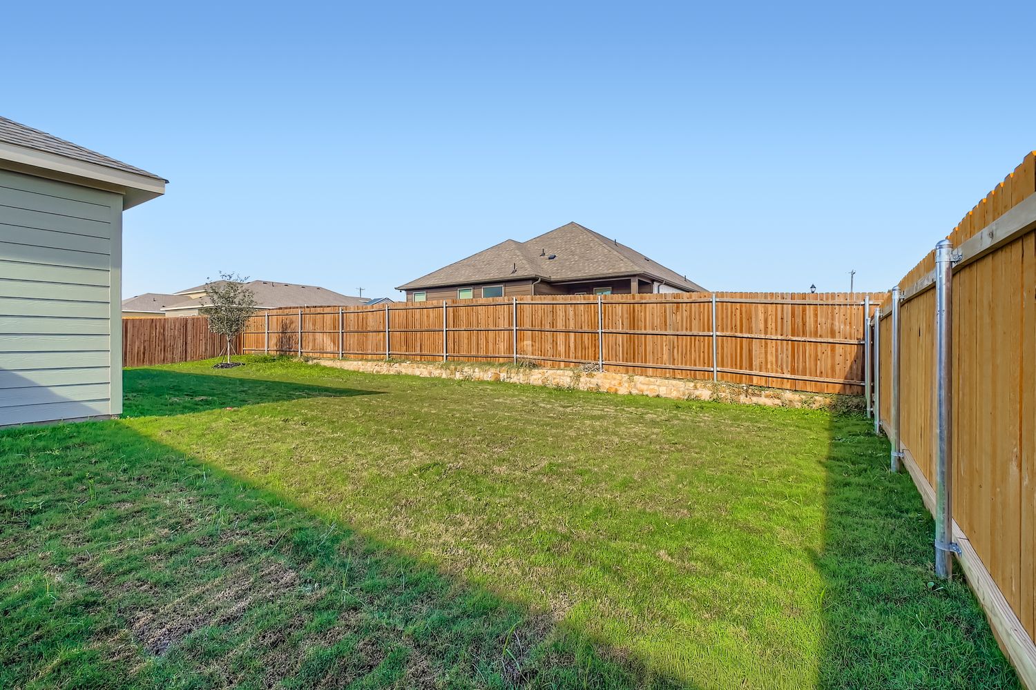 A fenced in yard with a house and trees in the background.