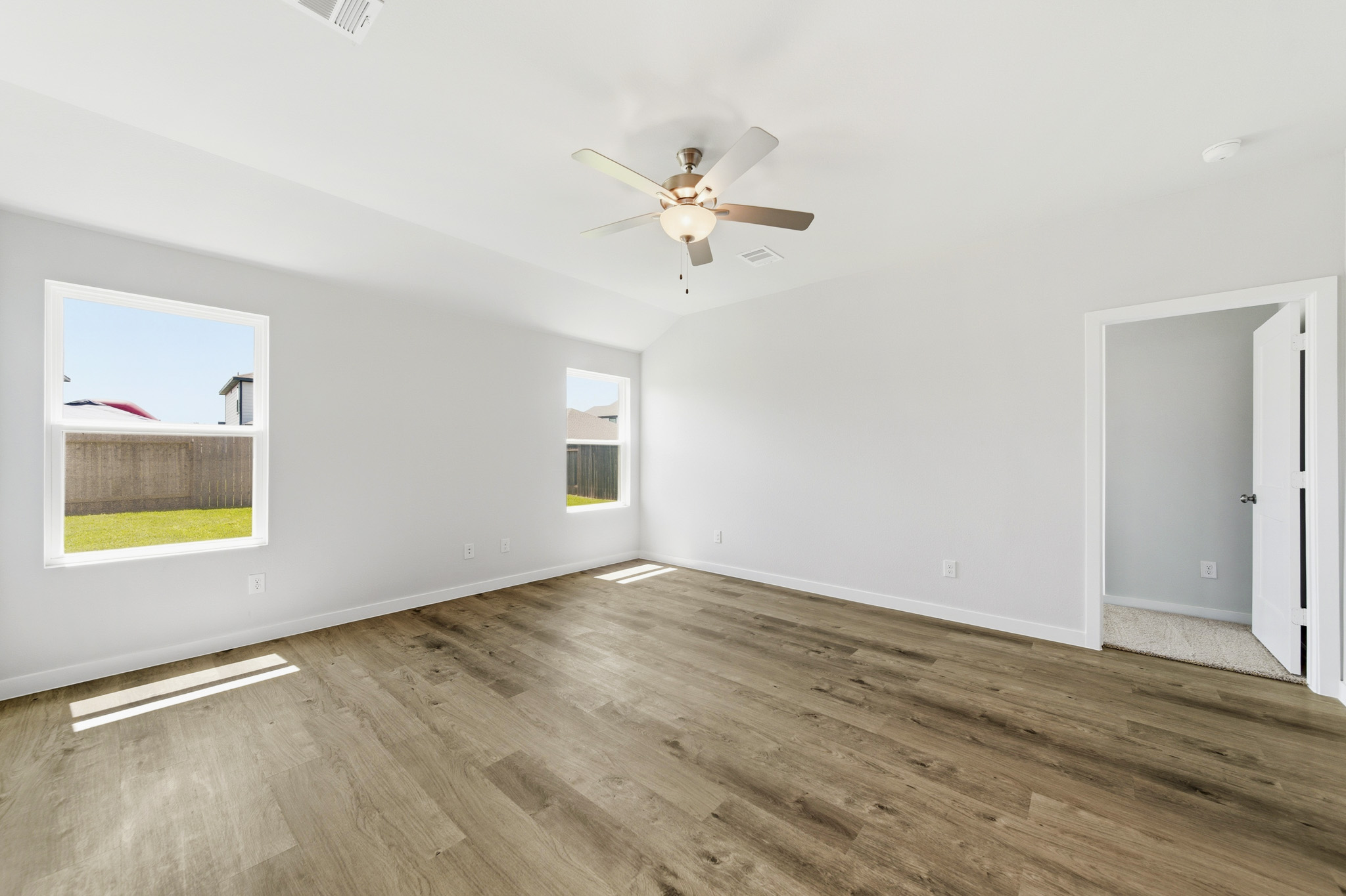 A room with a ceiling fan and a wood floor.