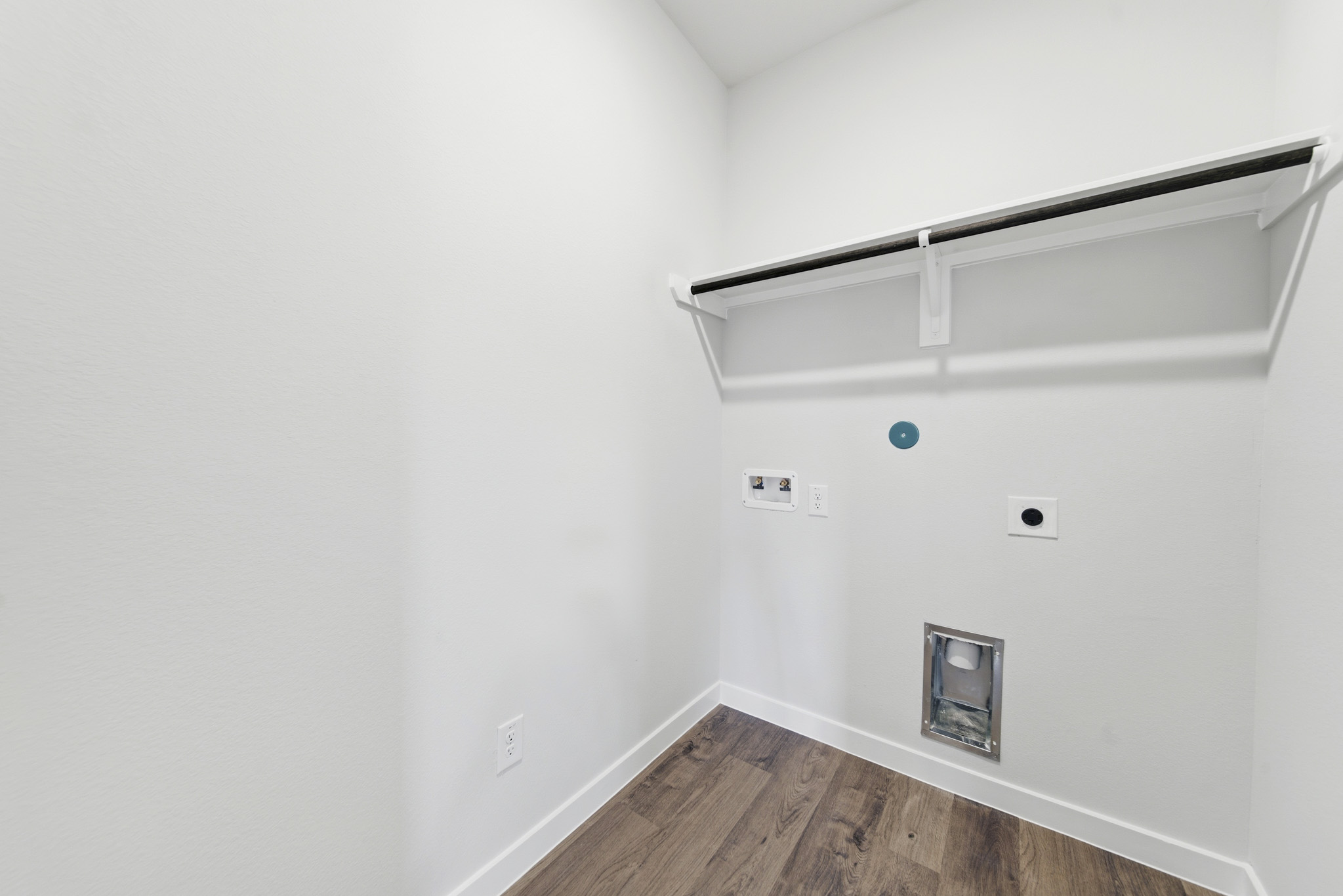 A white room with a wood floor and a white wall with a light.