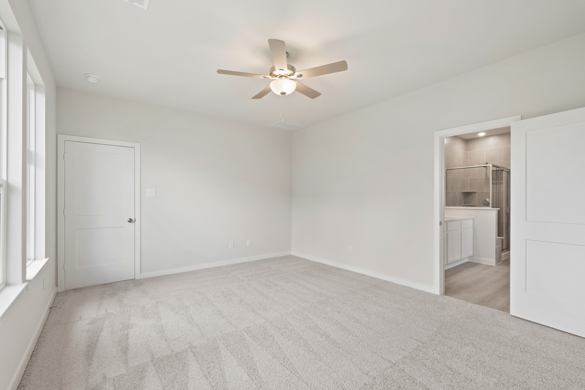 A room with a ceiling fan and white walls.