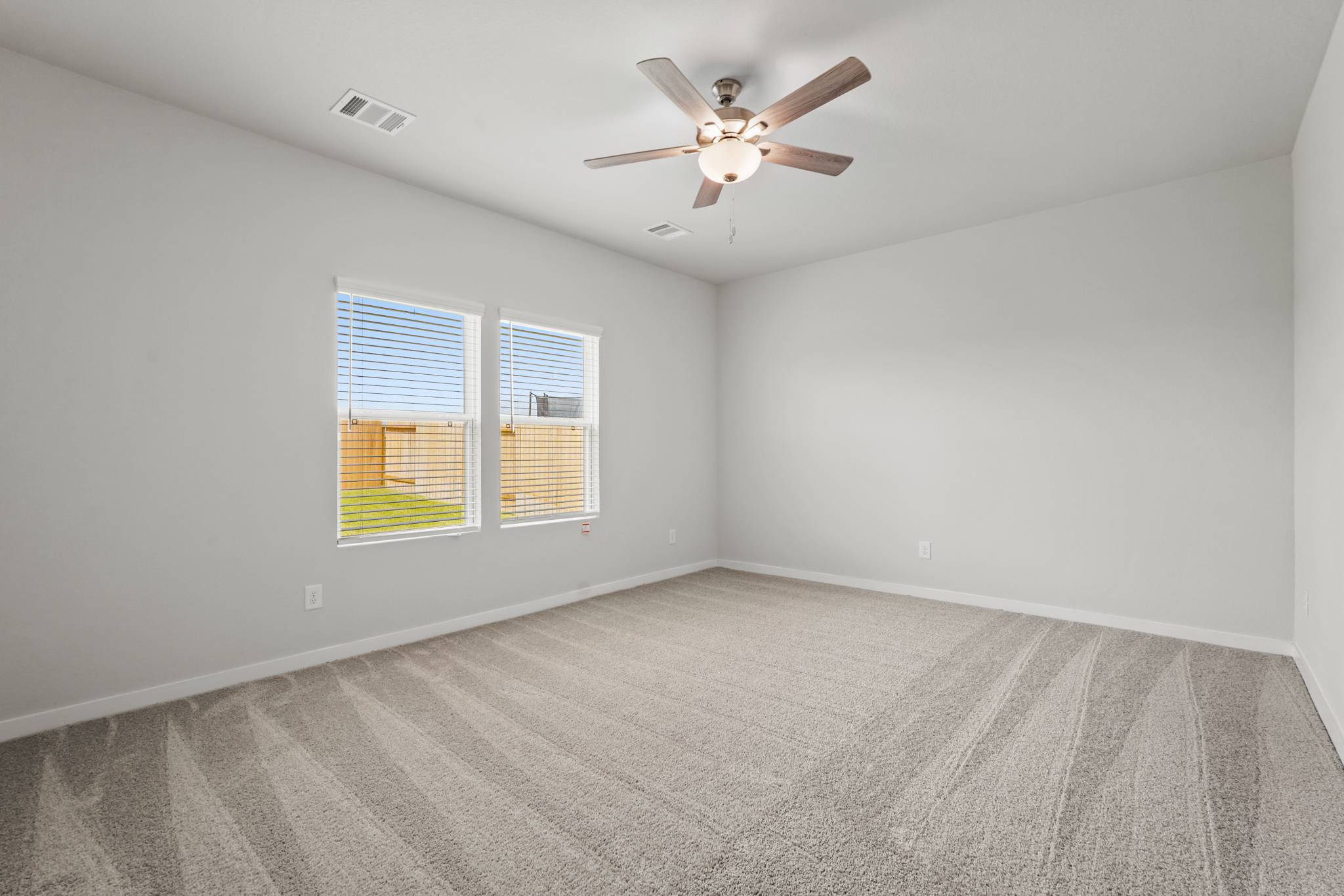 A room with a ceiling fan and a window with blinds.