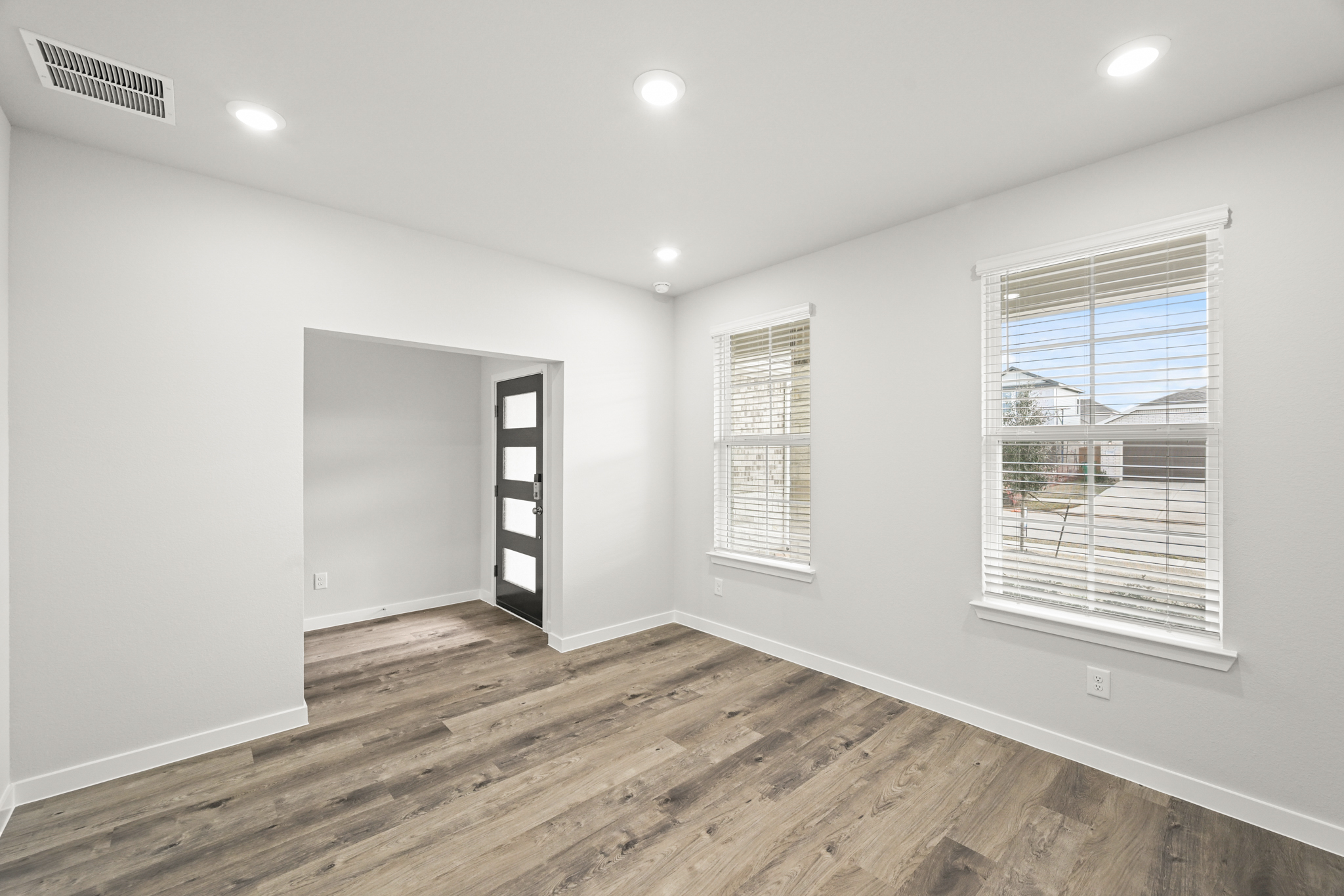 A room with a wood floor and a window with blinds.