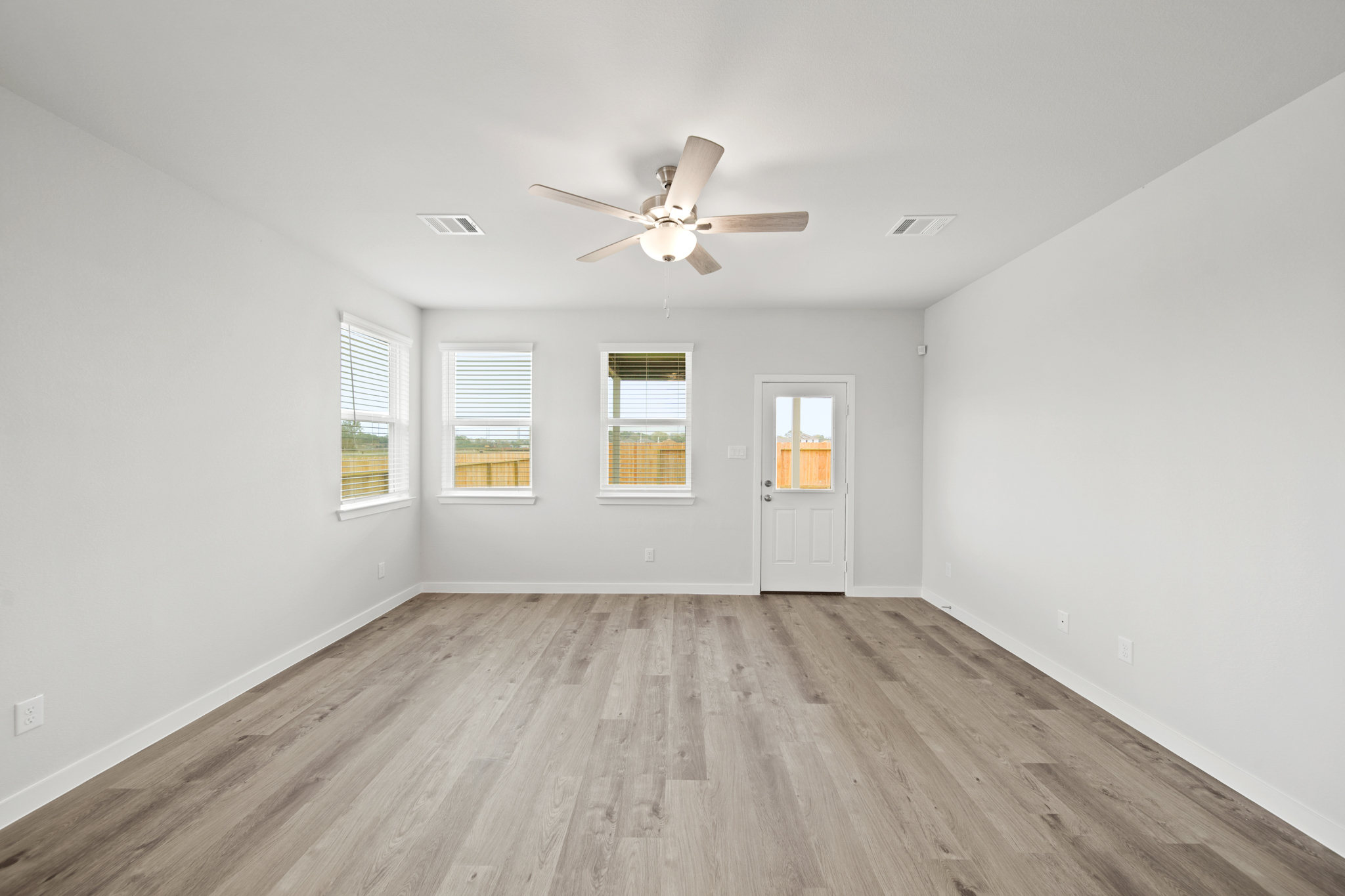 A room with a ceiling fan and a wood floor.