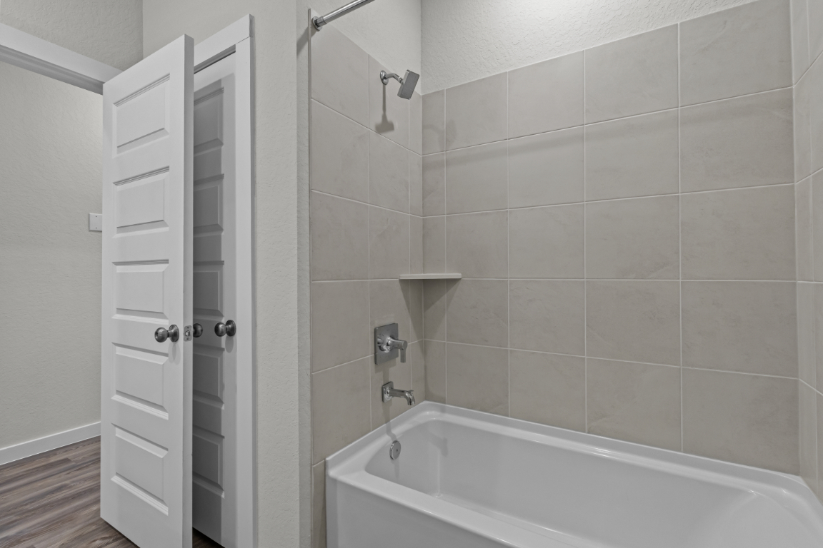 A bathroom with a shower unit and a bathtub.