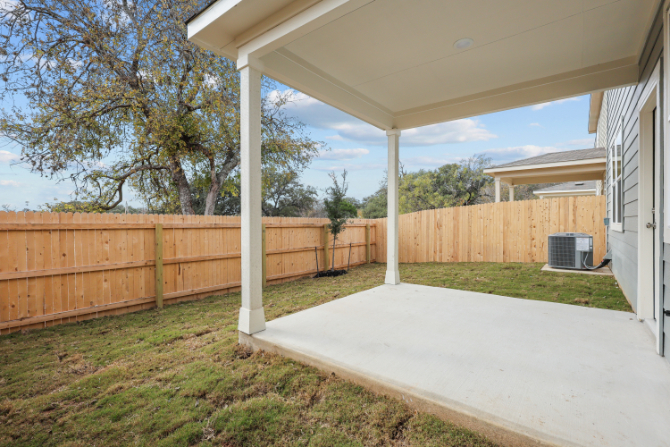 A fenced in yard with a wood fence and a tree.