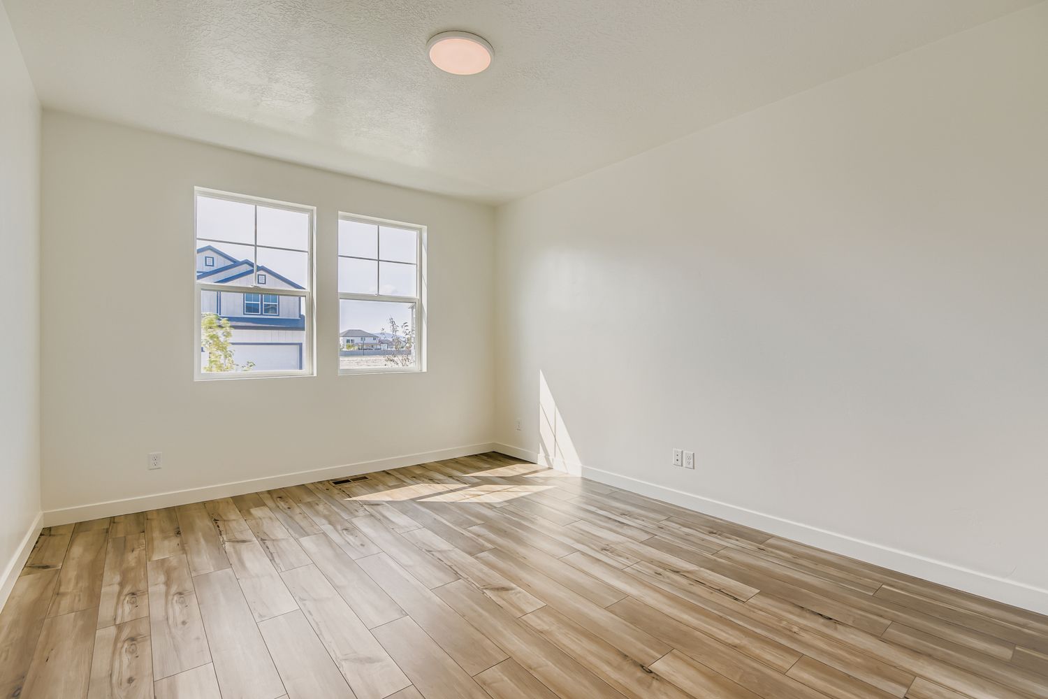 A room with a wood floor and a window with a painting on it.