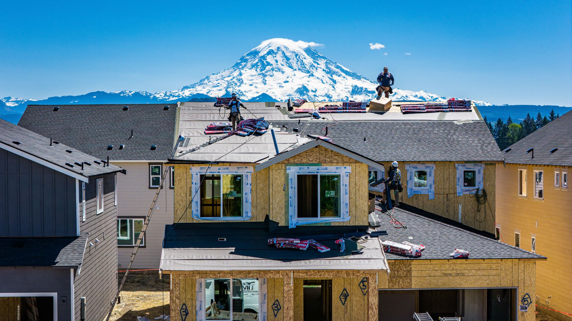 A group of men on top of a building with a mountain in the background.